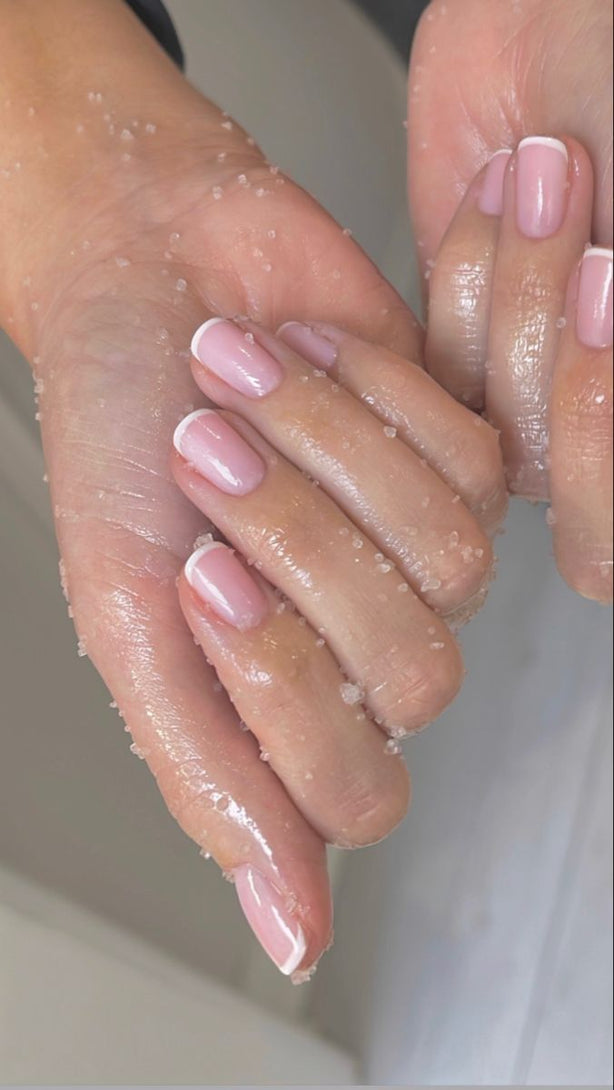 Close-up of two hands with pink nail polish on a neutral background